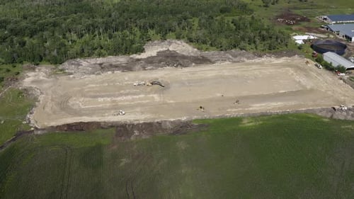 Luftaufnahme einer Baustelle auf einem Bauernhof. Schweres Gerät fährt auf der Baustelle herum