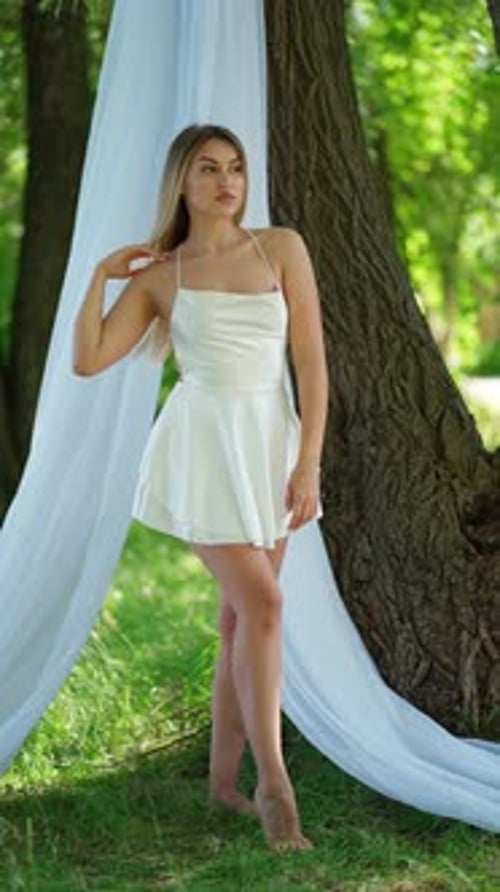 Young Woman Posing in White Dress in Forest