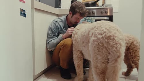 Man Cuddling with Dog in Kitchen at Home