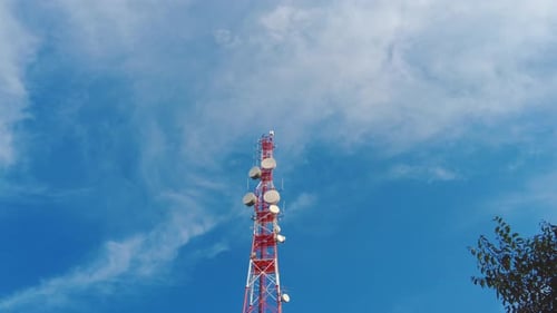 Large red and white pole with big cellular antennas and telecommunications radars day time upview wi