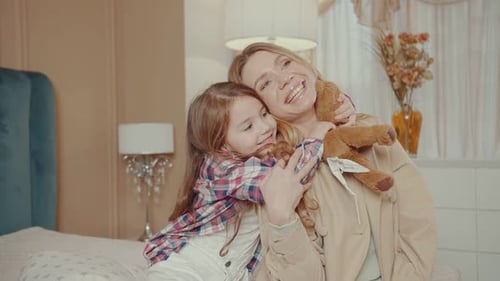 Loving Mother and Daughter Hugging in Bedroom