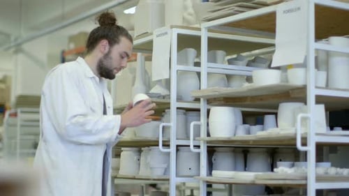 Male potter checking ceramic product in workshop