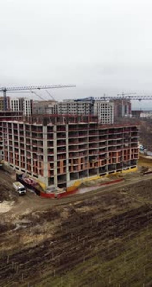 Vertical Aerial Drone Orbit Around Large Residential Construction Building With Cranes