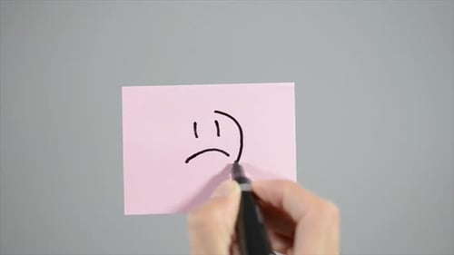 Drawing of a Sad Face on Pink Paper