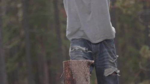 Man Splitting Wood With Axe Outside