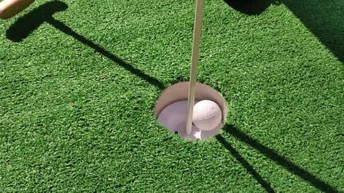 unrecognizable person playing mini golf