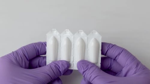 Hands in Gloves Hold White Suppositories