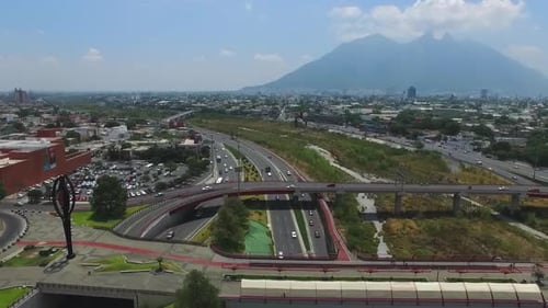 Aerial View of Busy City Highway Towards Large Mountain Peaks