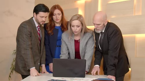 Team Discussing Data on Laptop in Modern Office