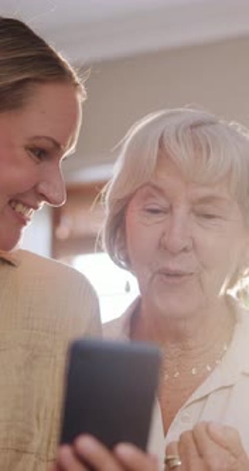 Two Women Looking at a Phone and Smiling