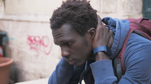 thoughts, concern - worried young black on the street man closes his eyes thinking