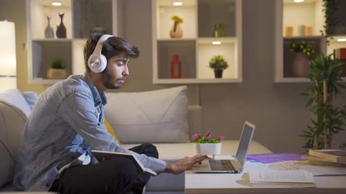 Young Adult Studying With Laptop and Notebook