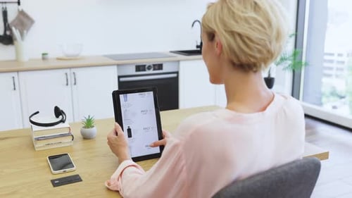 Woman Shopping Online with Tablet in Modern Kitchen