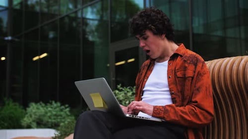 Young Adult Surprised by Laptop While Sitting Outside