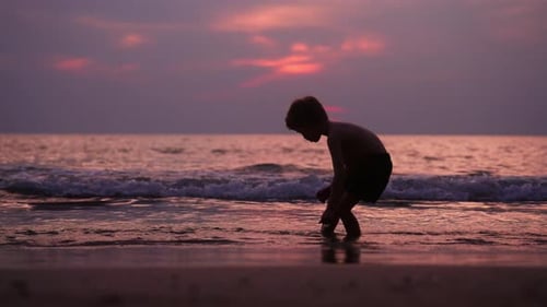 Child Plays on Beach at Sunset