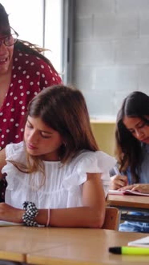 Teacher Assists Students at Desks in Classroom Setting