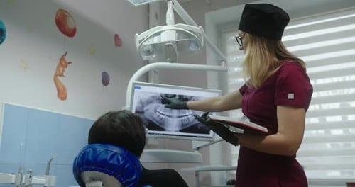 Kieferorthopädin zeigt ein Röntgenbild des Patienten, das über das Problem und den Prozess berichtet