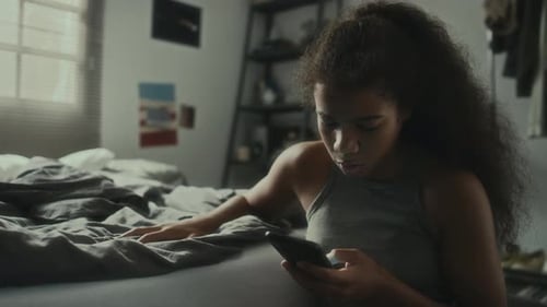 Frustrated Young Woman Using Phone on Bed
