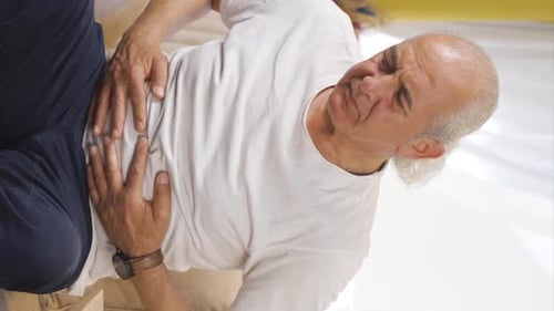 Vertical video of Old man experiencing stomachache.