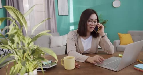 Woman Works on Laptop and Talks on Phone