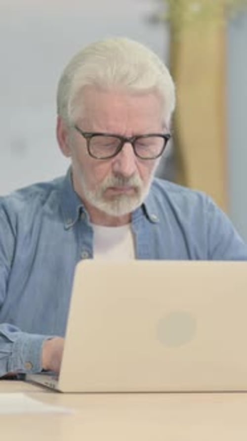 Old Man Typing on Laptop in Office, vertical video