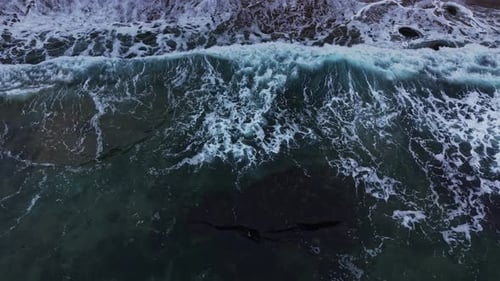 Waves crashing on the shore at a rocky beach during daylight hours