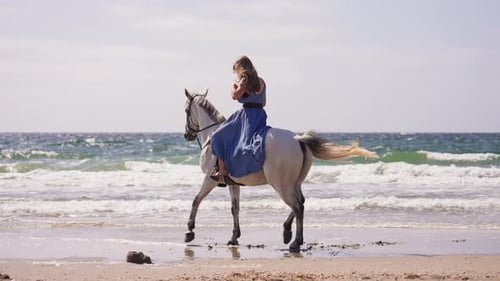 Girl In Blue Dress Horse Riding At The Beach