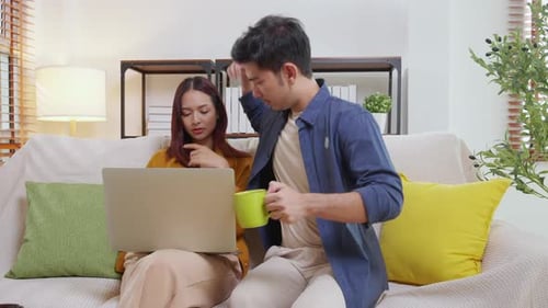 Couple Relaxing on Couch Using Laptop Together