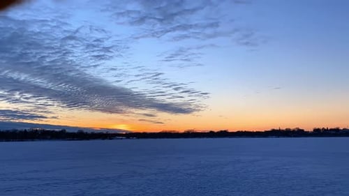 Time lapse clouds rolling a frozen lake in Minneapolis, Minnesota after sunset