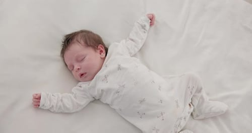 Infant Sleeping Peacefully in White Onesie on Sheet
