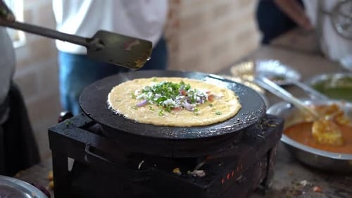 Plan rapproché d'un chef préparant une crêpe Besan ka chilla ou à la farine de pois chiches. Chilla ou Besan Cheela est