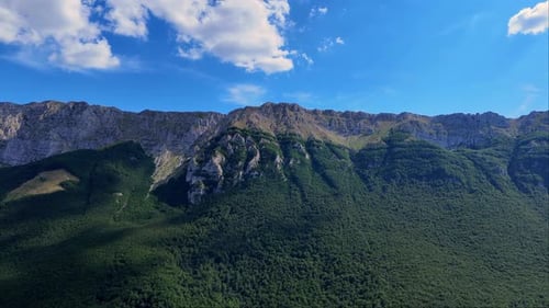 drone flies over a rocky mountain, clouds in the sky.