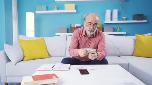 Man Counting Money at Home on the Sofa
