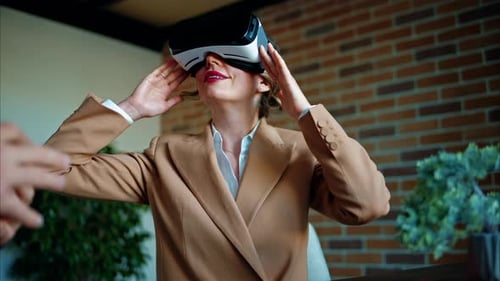 Woman impressed while using a Virtual Reality headset in an office, man hands gesturing