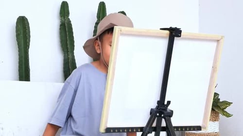 Young Boy Contemplates Blank Canvas on Easel Indoors