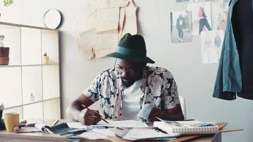 Male fashion designer sketching at desk in studio