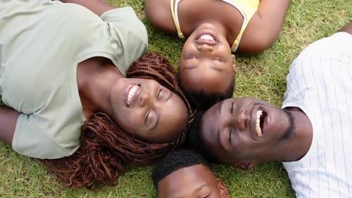 Family Lying Together on Grass, Smiling Happily
