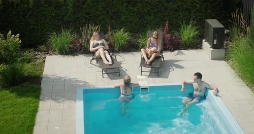 Family with Dog Relaxing By the Pool