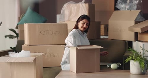 Woman unpacking cardboard boxes after moving into new house