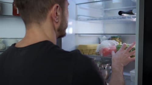 Man Getting Vegetables from Fridge in Kitchen