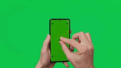 Male Hand Holding a Smartphone with Vertical Green Chroma Key Screen Isolated on Green Mobile Phone