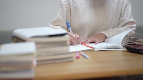 Person Studying and Writing Notes at Table