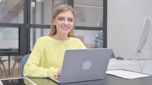 Smiling Woman Works on Laptop in Bright Office