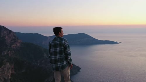 Young Man Standing on Top of the Mountain and Enjoying Scenery Sunset