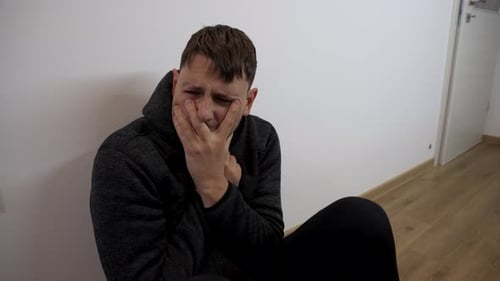 Man sitting alone crying in emotional pain