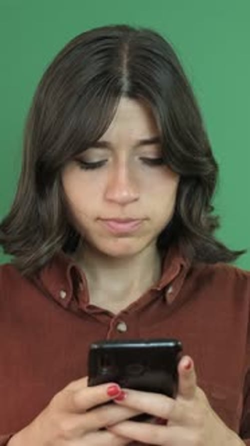 Young Adult with Smartphone in Front of Green Screen