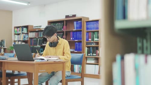 Student, thinking and man in library, laptop and typing with education, university and knowledge.
