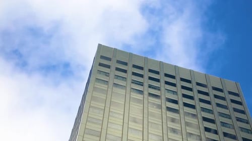 Blue sky and clouds reflect interesting patterns onto the windows of a building