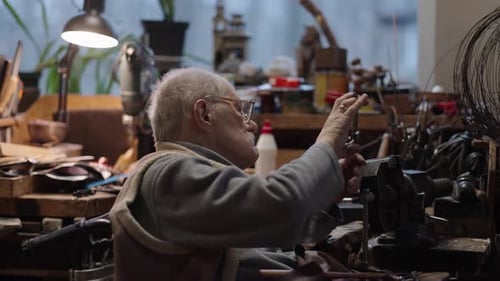 Senior Elderly Master Jeweler in Wheelchair Works in a Workshop