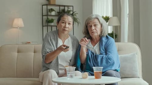 Senior Women Watching Television on Sofa at Home